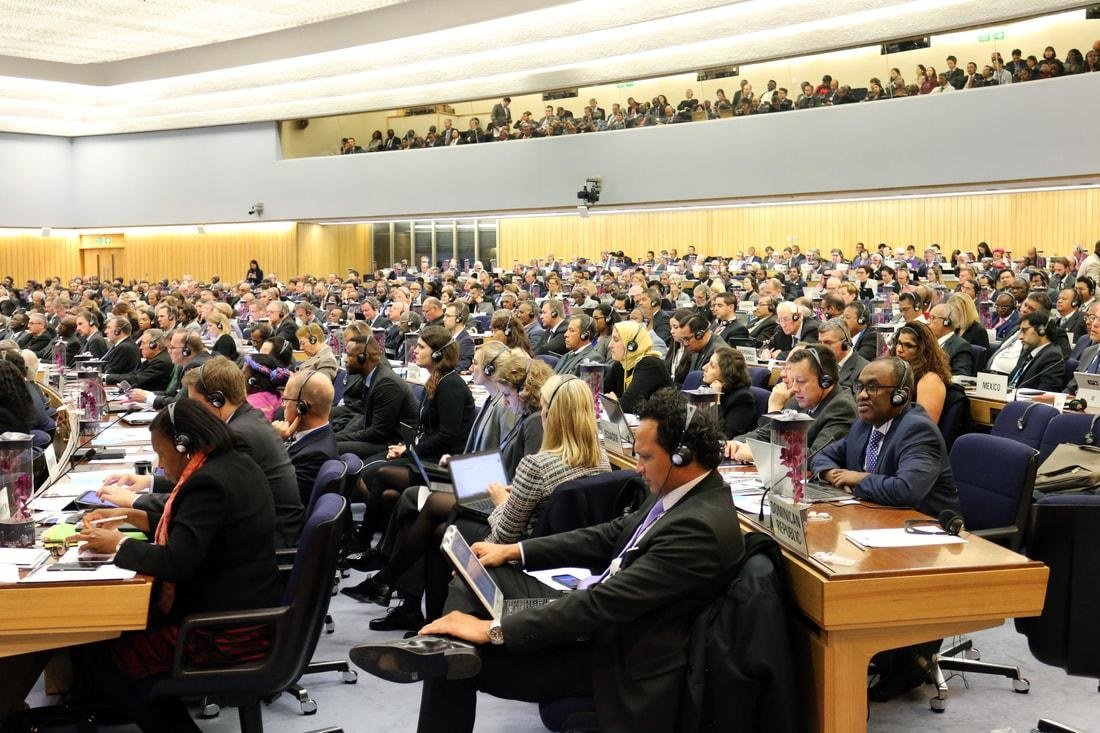 Delegates seated in an assembly hall with interpretation headsets